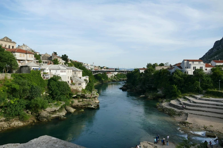 the river is very clear with some houses and buildings on the hillside