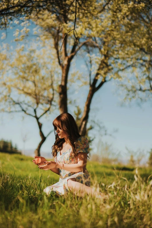 woman sitting in the grass holding a cell phone