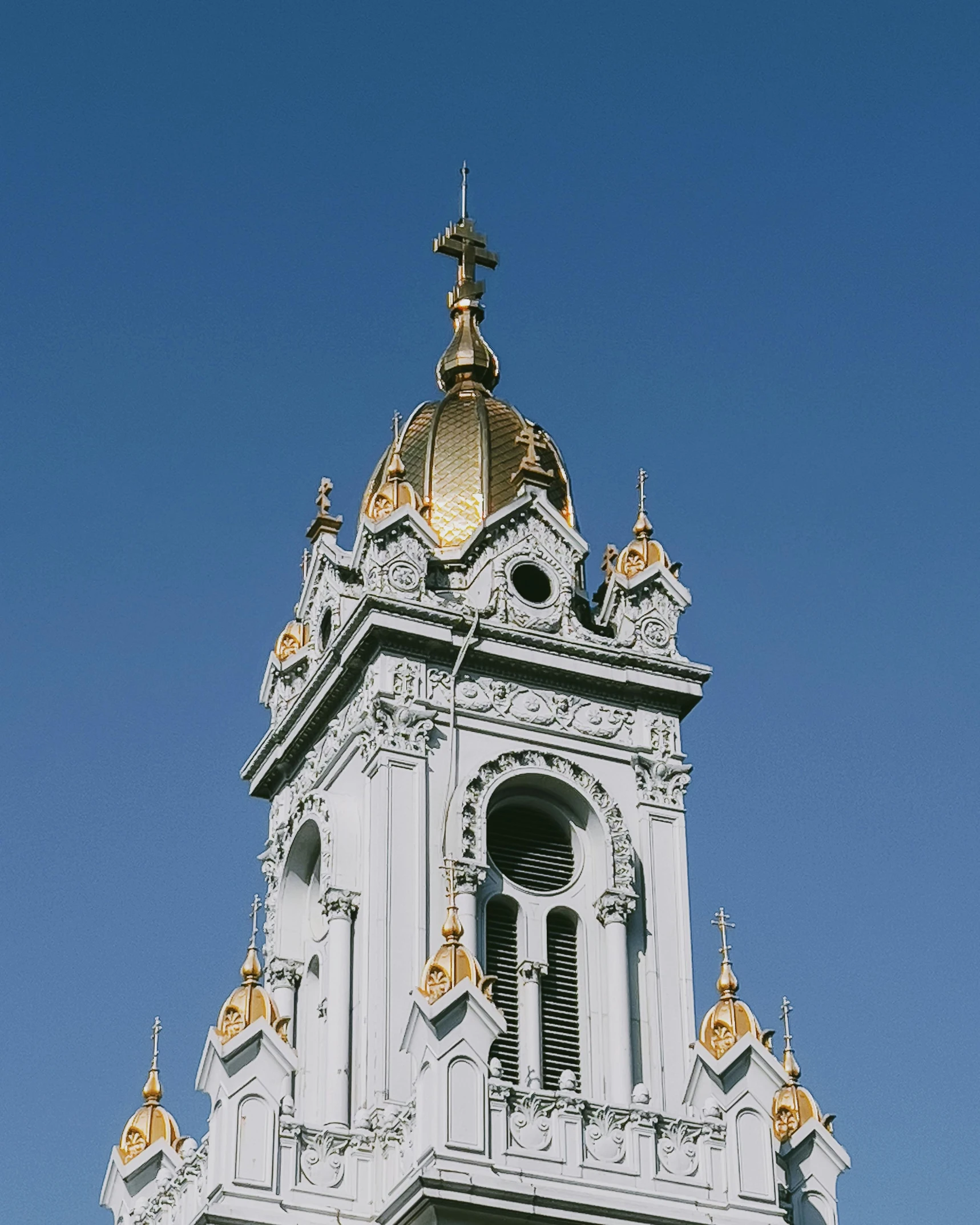 a very tall white clock tower with gold domes