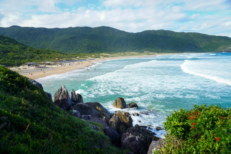 an overlook view of a sandy beach with several people in it