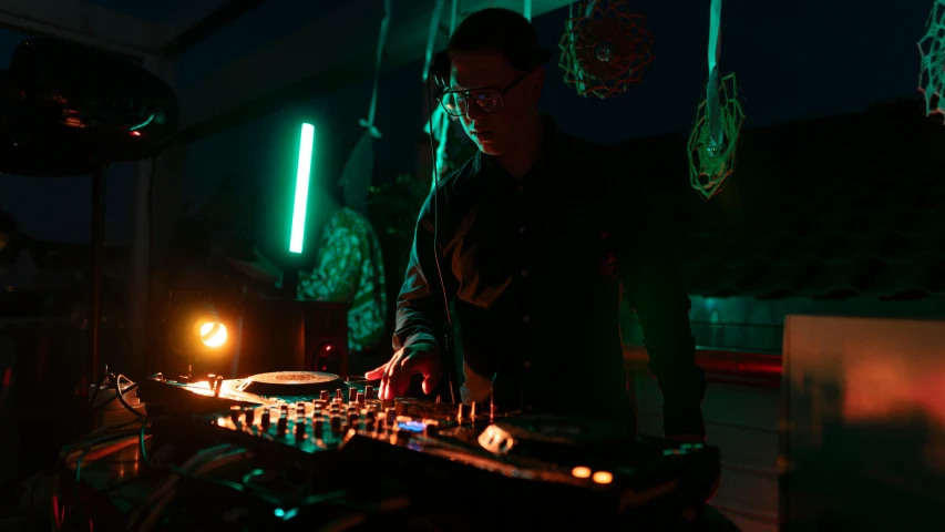 a man mixing a music set with headphones in a dark room