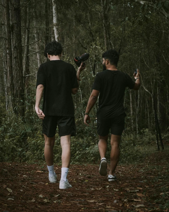 two men walking through the forest holding soing in each hand