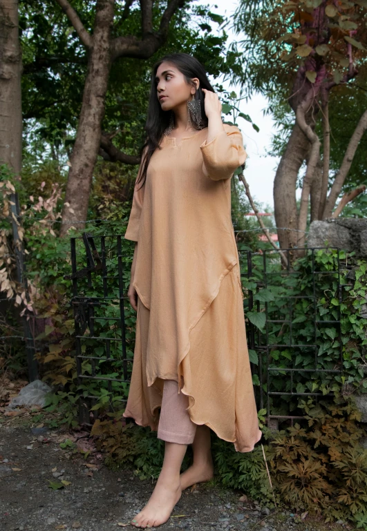 a woman stands beside the fence, posing