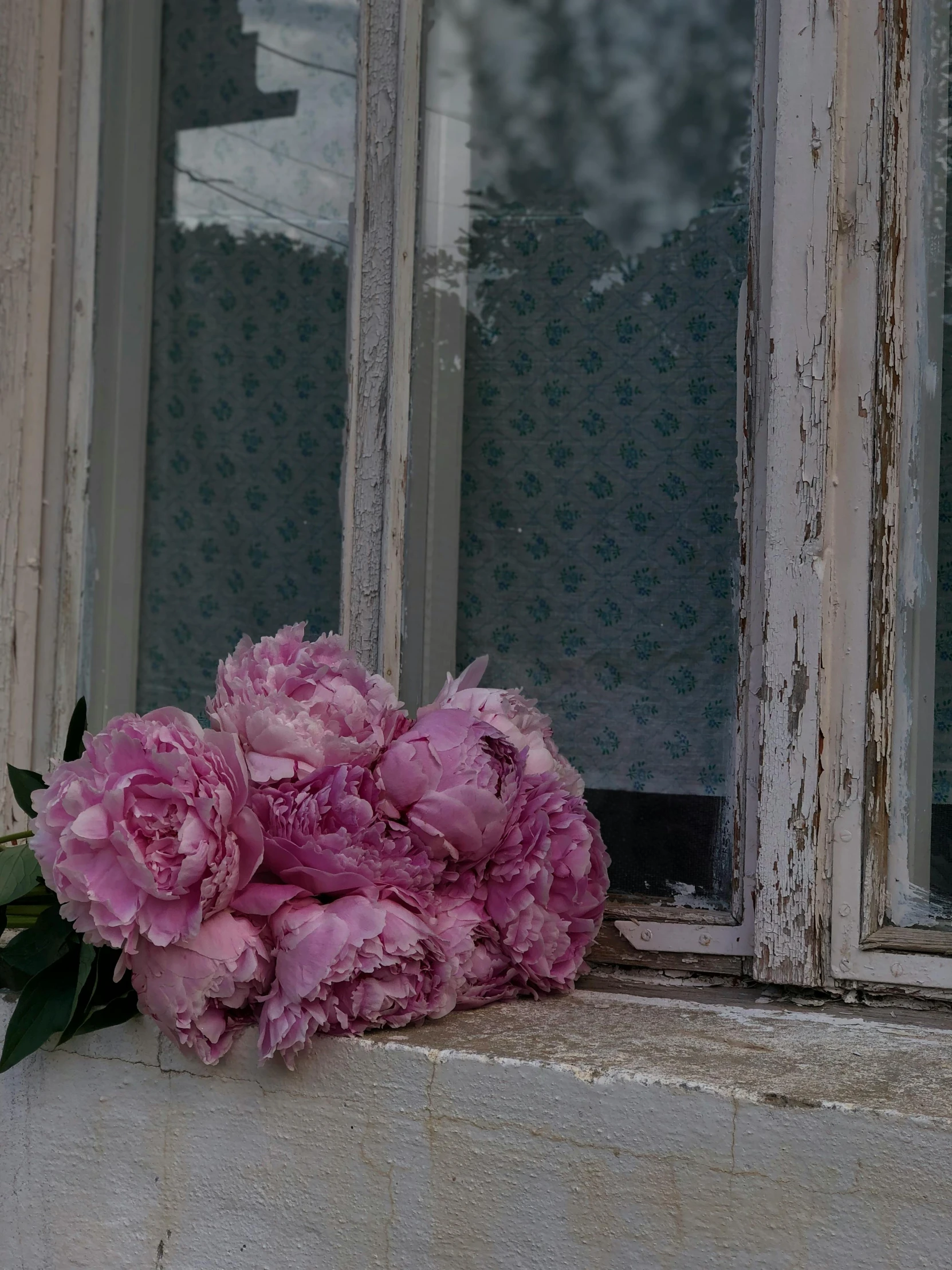 flowers sit on the windowsill outside an old, worn down building