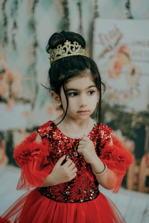 a girl in a red dress wears a tiara