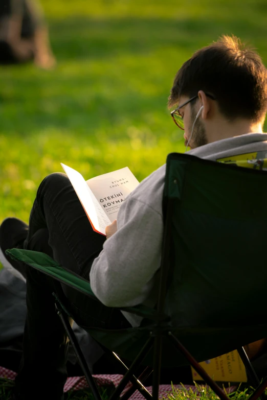the man is relaxing in his chair while reading the book