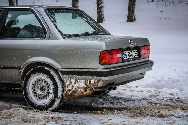 the back of a gray car parked on a snowy road