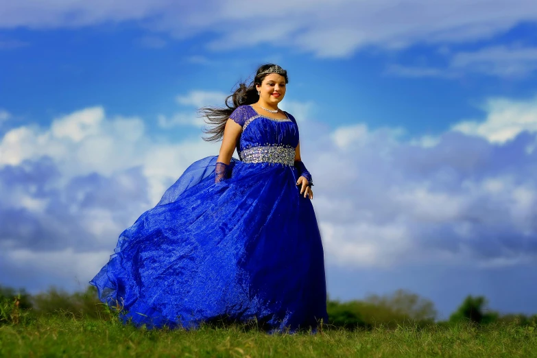 the woman is posing in the large dress on the grass