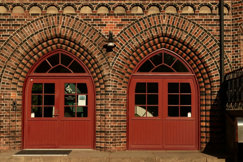 a brick building with arched doors and two windows