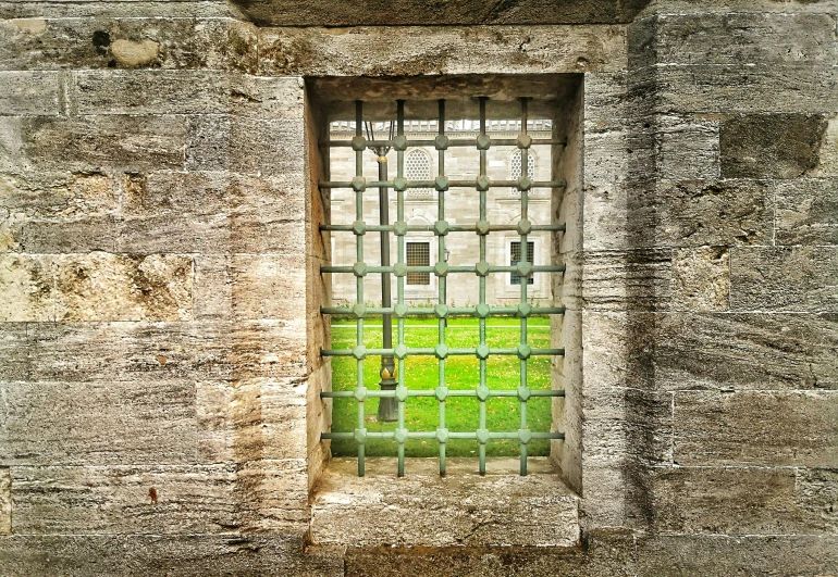 an image of a window behind bars on the outside wall