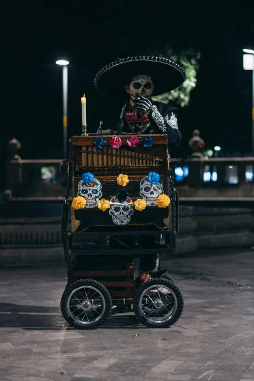 a skeleton wearing a mexican hat, riding a cart with skulls