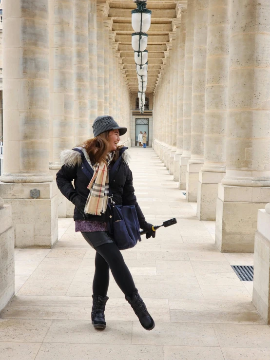 a woman poses for the camera in front of columns