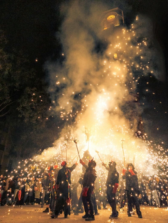 people holding torches in the sky next to a fireworks display