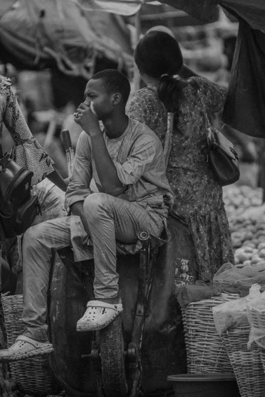 a man sits on top of some luggage in front of many people