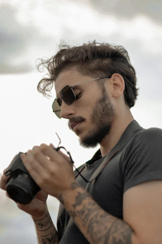 man with glasses and tattoos using a cellphone