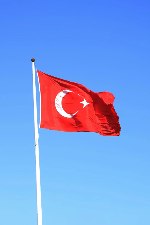 the flag of turkey flying against a blue sky