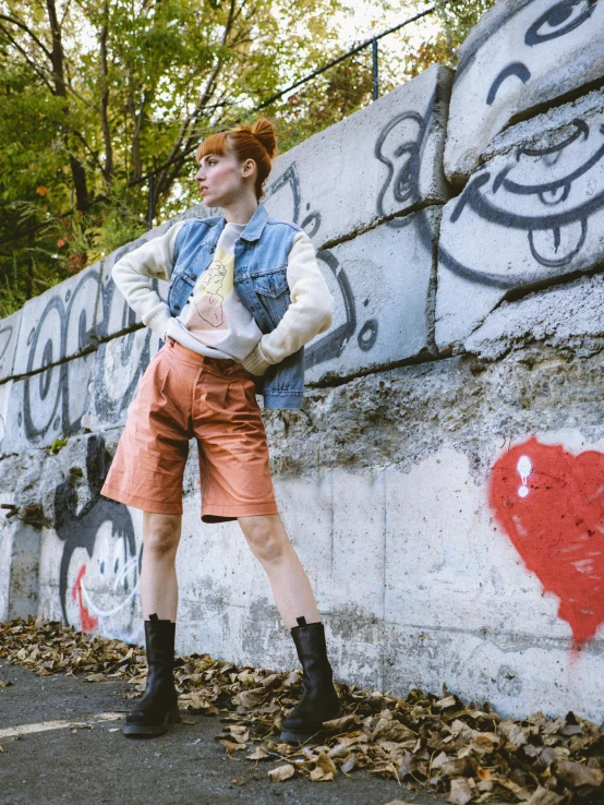 a woman leaning against a graffiti covered wall