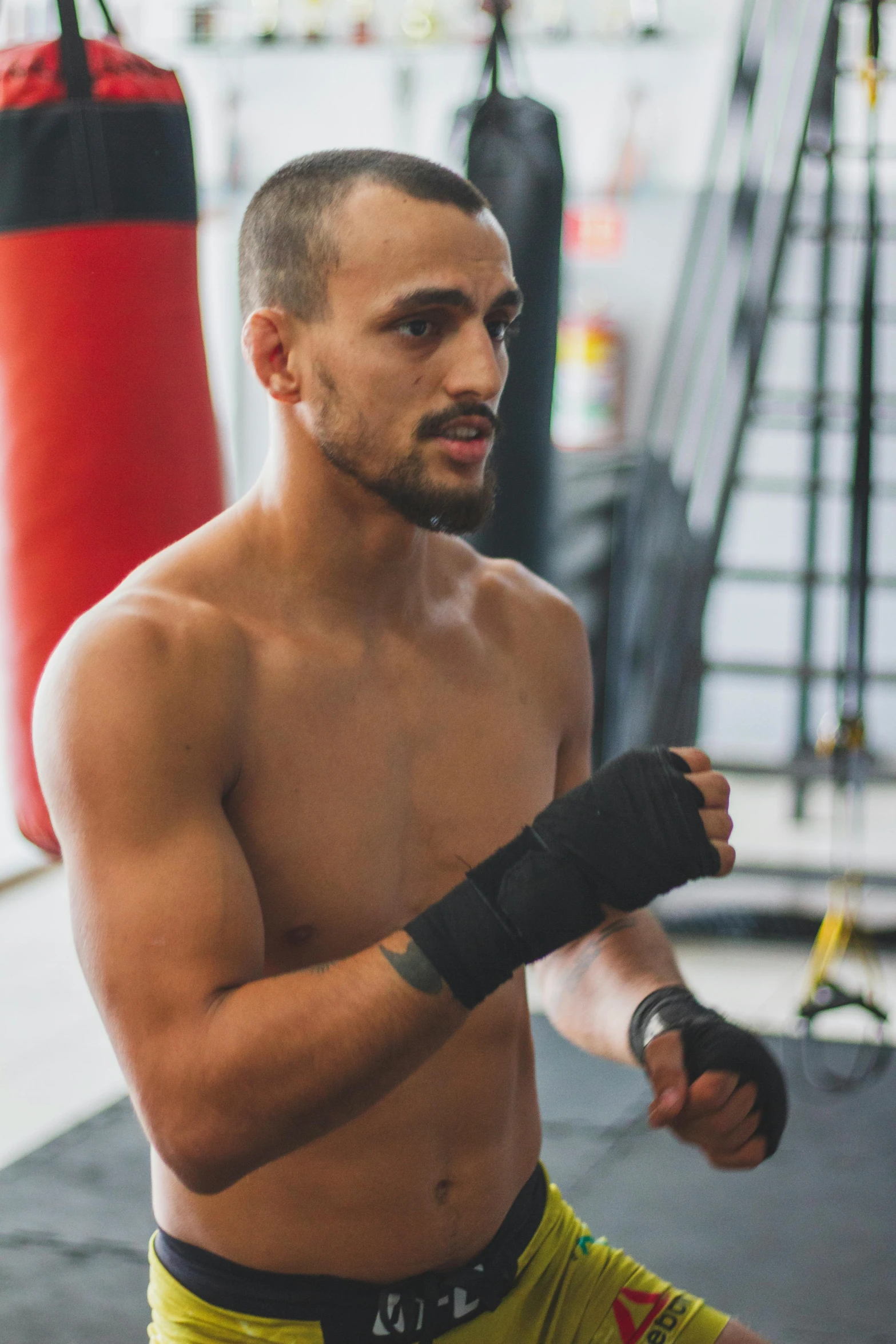 a man with a boxer handwrapps stands in a gym