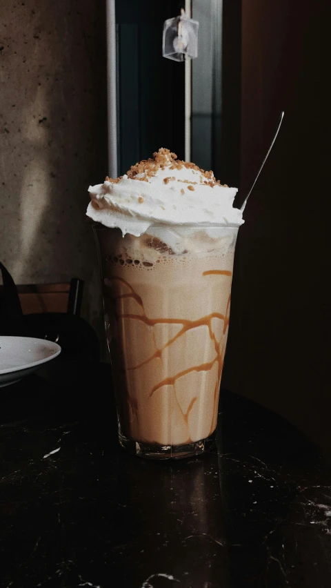 a tall glass of drink on the table in a dark room