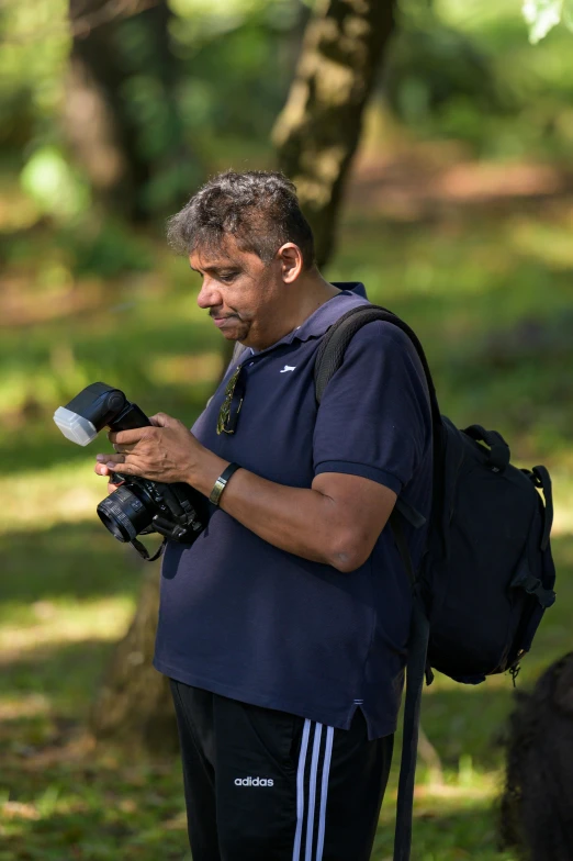 a man wearing black stands in a grassy area looking at his camera