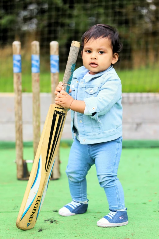 a baby with a bat poses for the camera