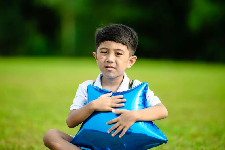 a boy in white shirt holding a blue pillow