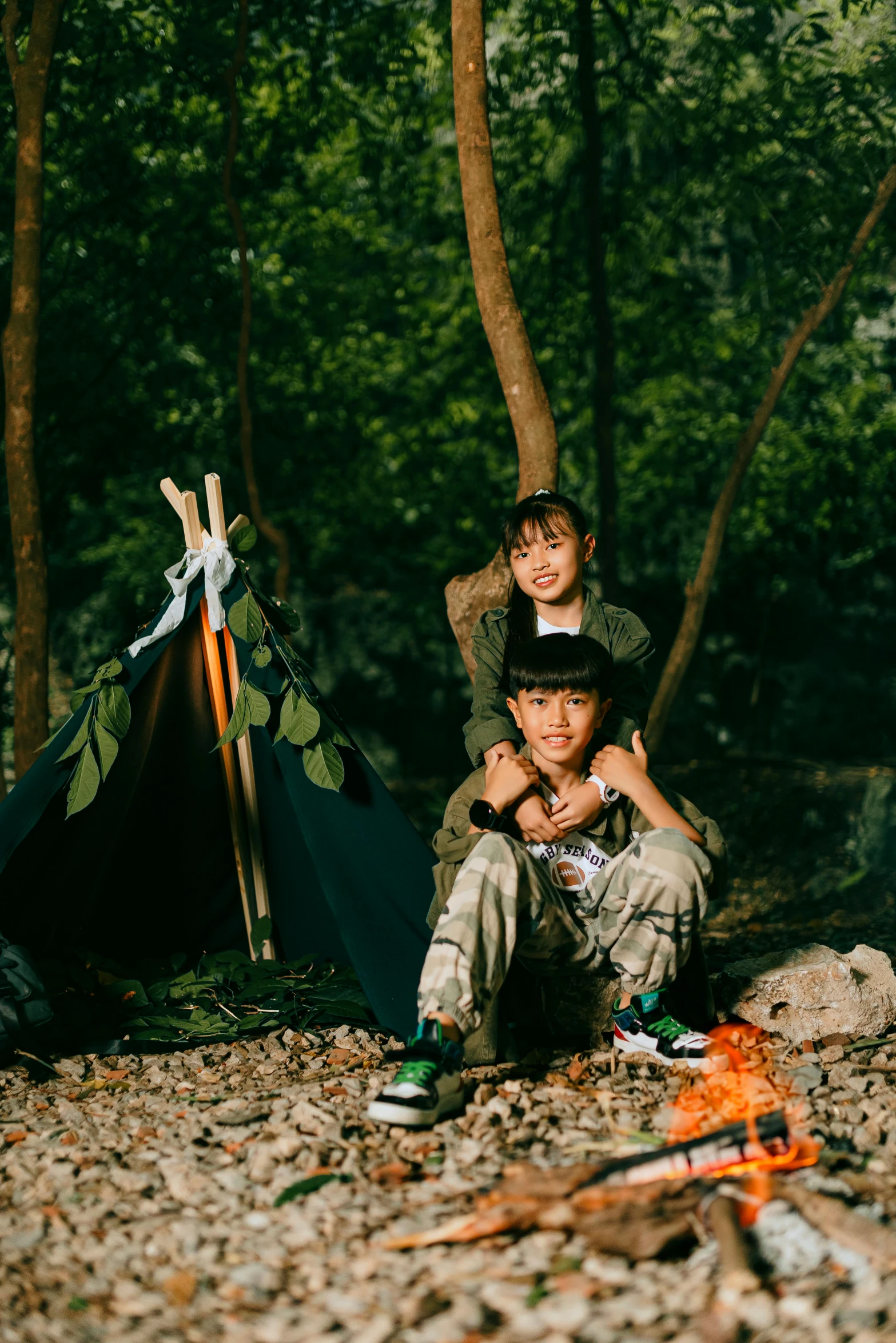 two children are setting up camp site with an open canvas tent in the background