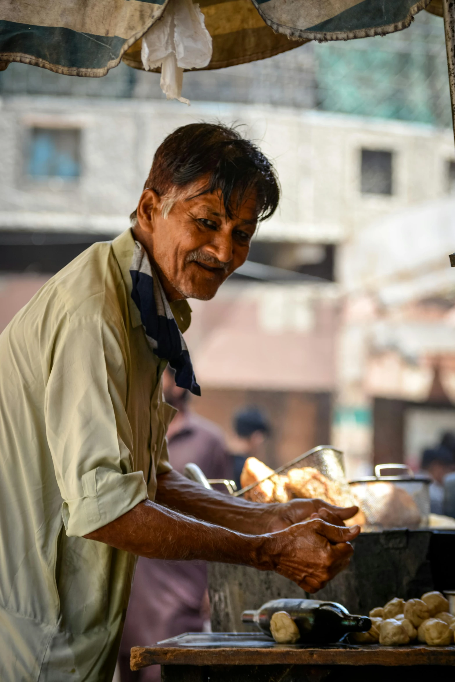 a man making bread sticks and smiling while another watches