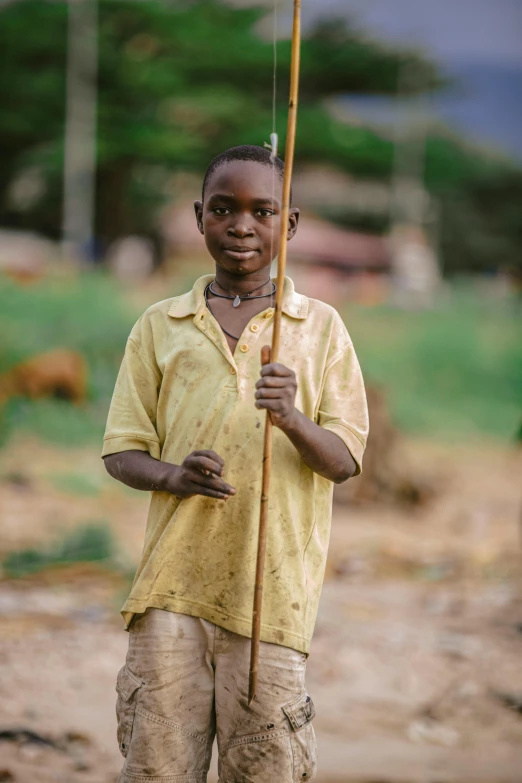 a boy holding a pole while walking on dirt