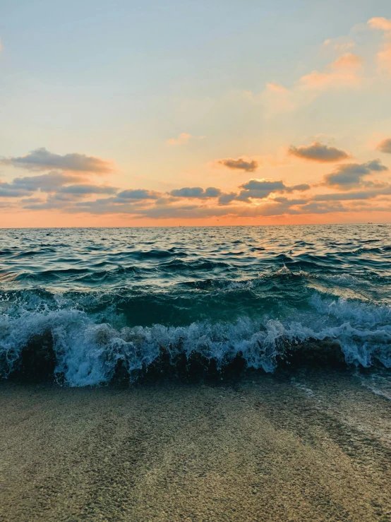 a beach with a very low wave and a cloudy sky