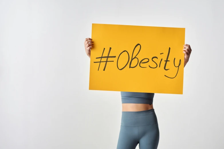 a woman is holding a yellow sign saying obety