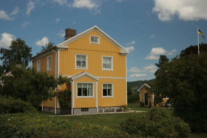 a yellow house on the edge of a grassy hill