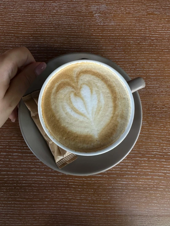 a cup of latte on a saucer with the shape of a heart on it