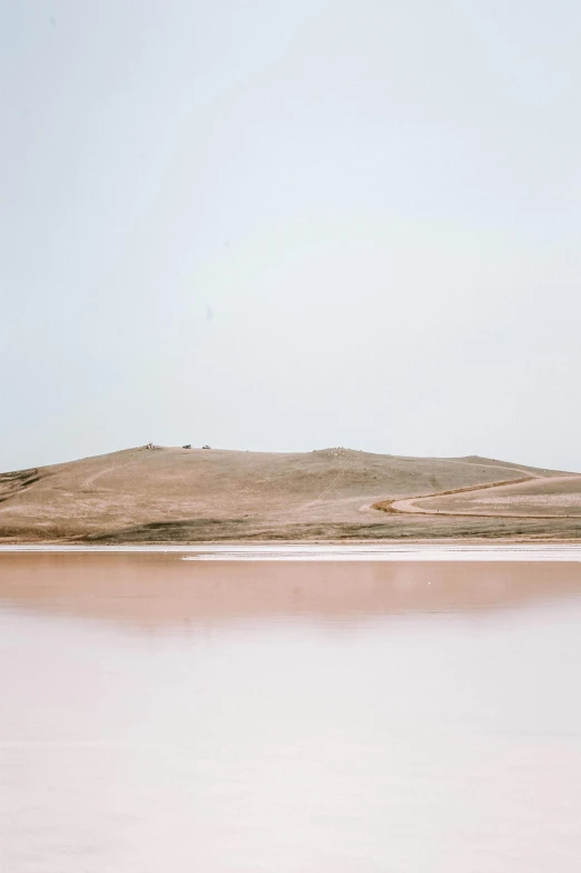 water on the shore with sand hills and water in background