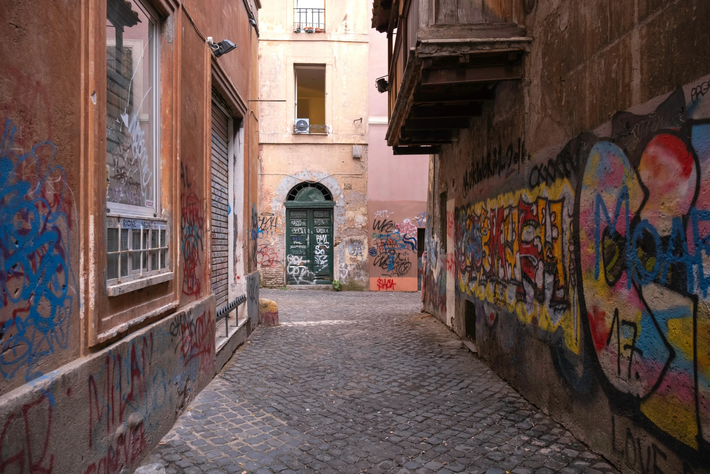 graffiti covered buildings next to a cobblestone alleyway
