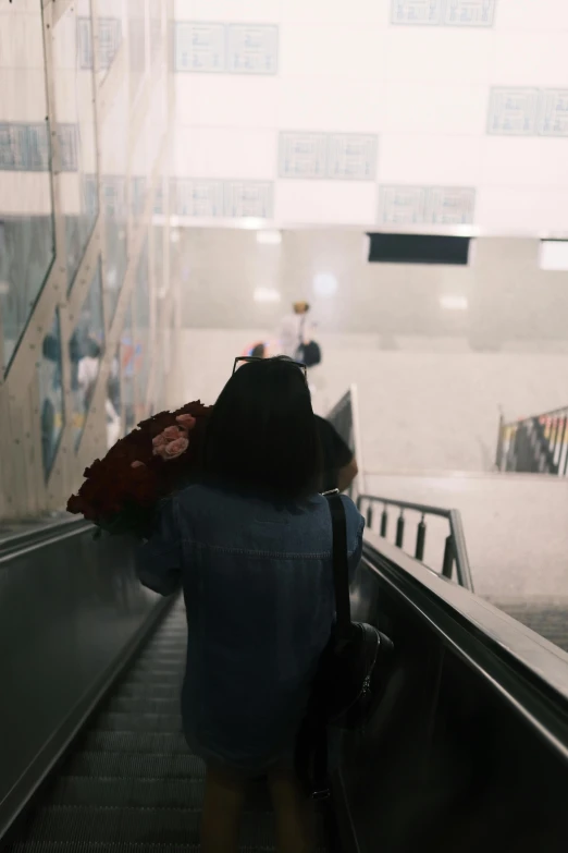 woman riding an escalator with an umbrella and backpack