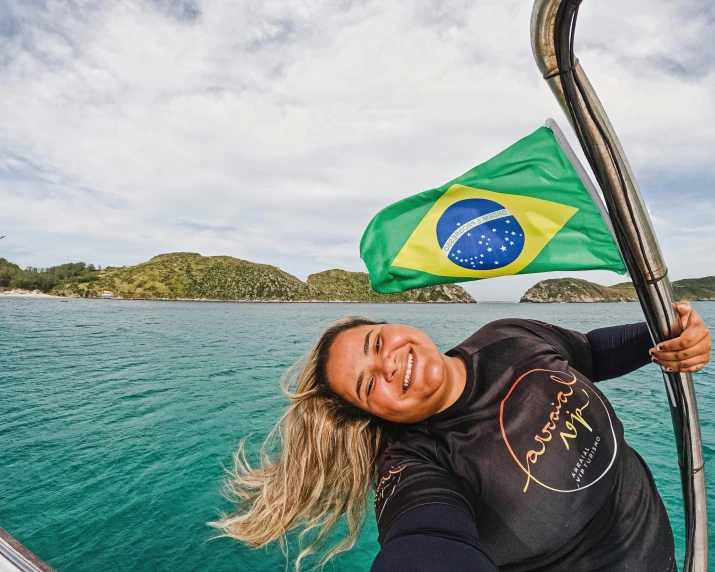 a woman smiling while holding a flag in front of her