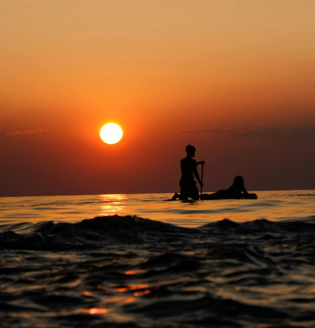 a man standing in the ocean while holding a paddle