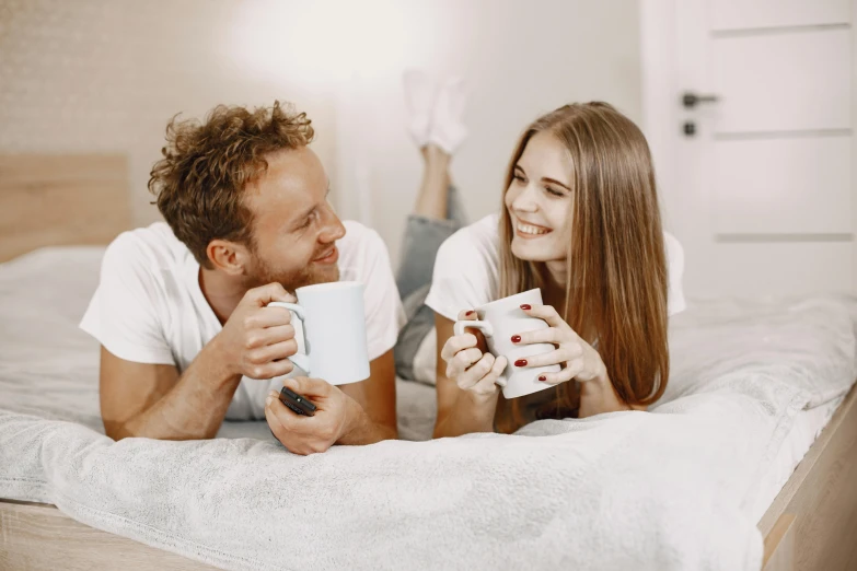 a man and woman laying on a bed together smiling