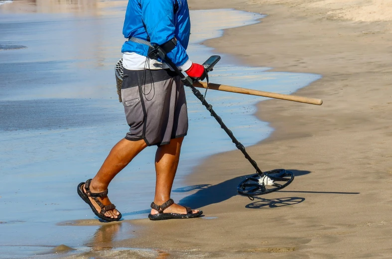 a man holding a stick standing on top of a beach