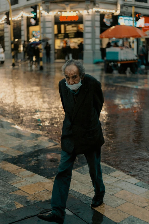 an elderly man standing on a city street in the rain