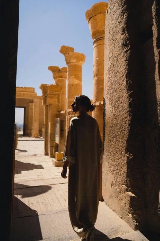 a man in an ancient egyptian setting walks along an alley