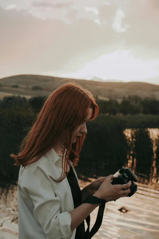 a woman holds her camera in front of the water