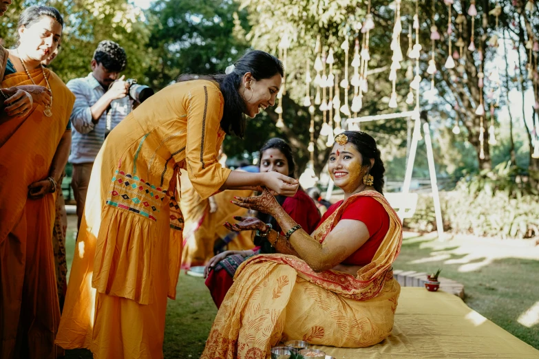two women in indian saris giving each other an engagement ring
