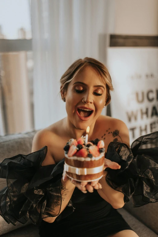 a woman holding a cake with candle lite inside