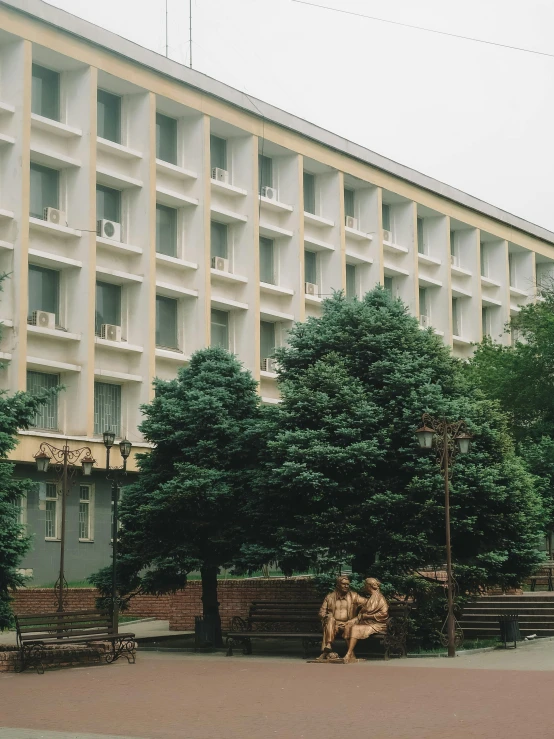 a couple of people sitting on top of benches next to a building