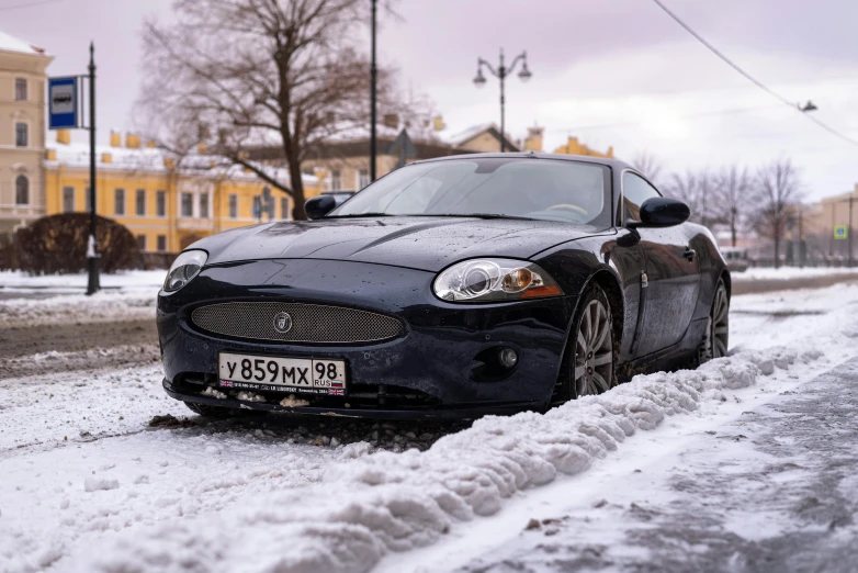 a car parked next to a snowy sidewalk in front of buildings