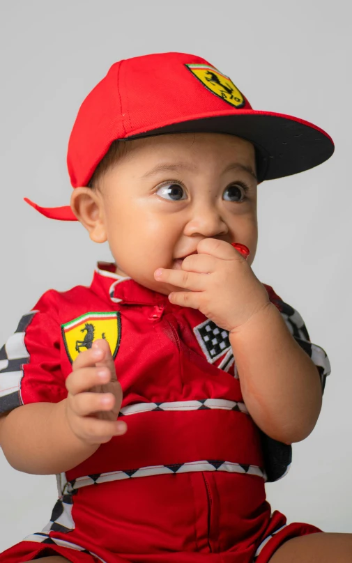 a baby in a red racing uniform sitting