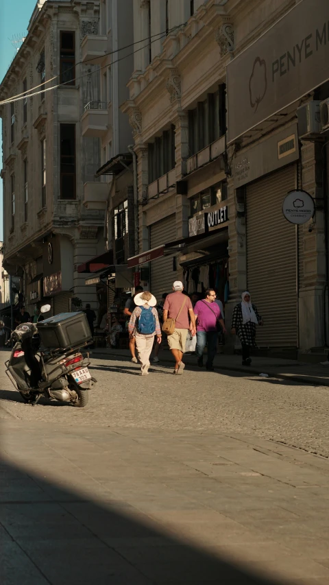 several people walking down a city street near a motorcycle