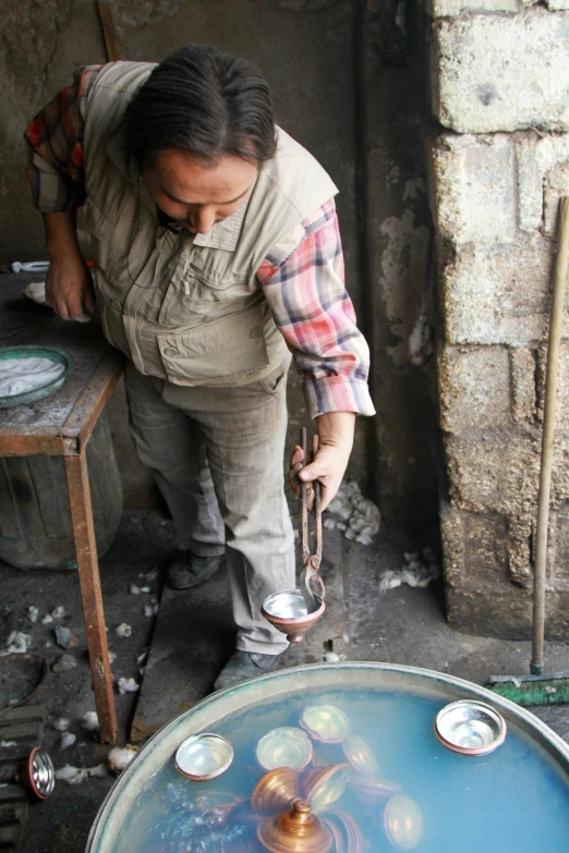 a man in plaid shirt pouring soing out of a pot